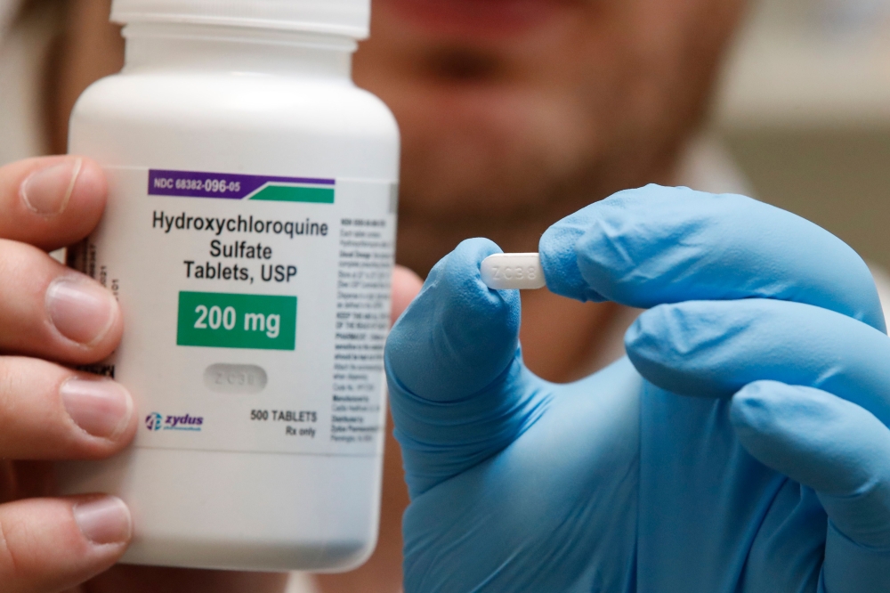 A pharmacy tech holds a bottle and a pill of Hydroxychloroquine at Rock Canyon Pharmacy in Provo, Utah, on May 20, 2020. US President Donald Trump announced May 18 he has been taking hydroxychloroquine for almost two weeks as a preventative measure agains