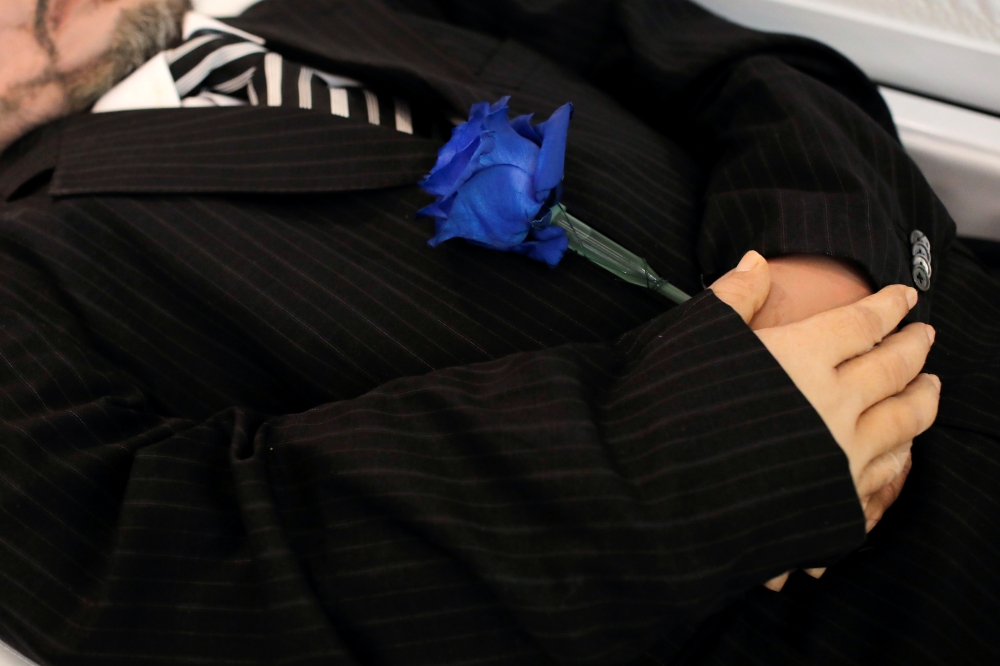 A blue rose is seen placed in the hands Jose Holguin, 50, originally from the Dominican Republic and who died of complications related to the coronavirus disease (COVID-19), during his viewing service at International Funeral & Cremation Services in the H