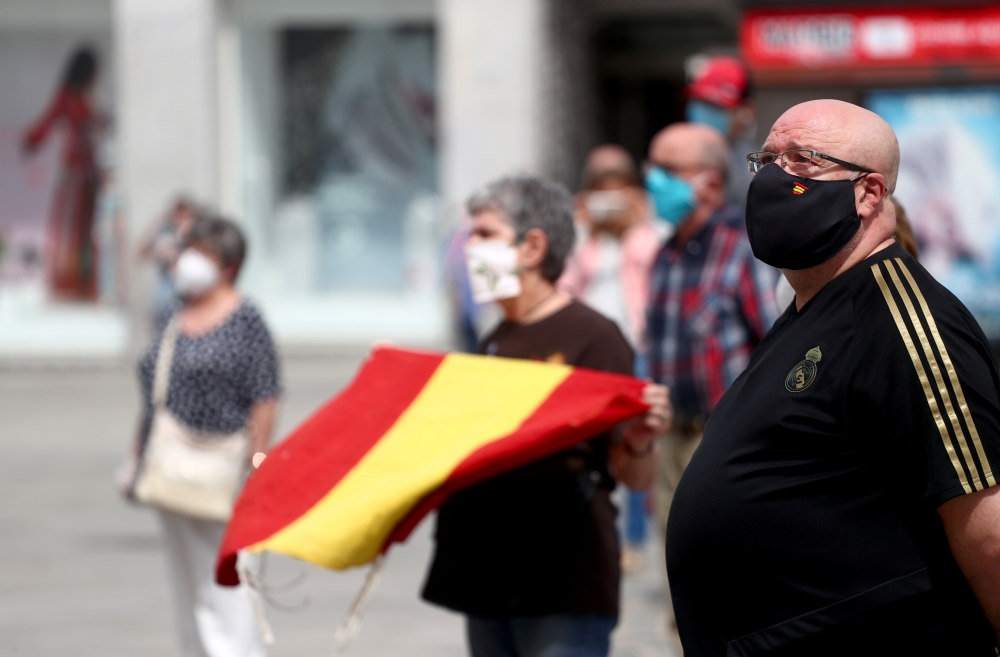 People wearing protective face masks stand during a daily minute of silence to commemorate victims of the coronavirus disease (COVID-19), at Puerta del Sol square in Madrid, Spain, May 26, 2020. REUTERS/Sergio Perez
