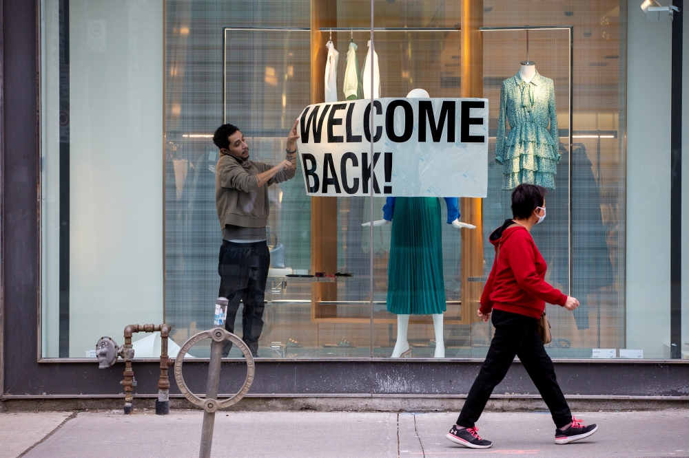 FILE PHOTO: An employee at Zara puts up a sign during a phased reopening from the coronavirus disease (COVID-19) restrictions in Toronto, Ontario, Canada May 19, 2020. REUTERS/Carlos Osorio/File Photo
