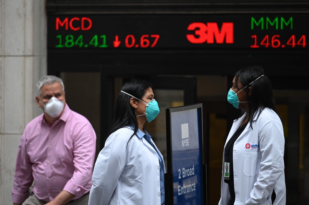 Traders wearing masks arrive before the opening bell at the New York Stock Exchange (NYSE) on May 26, 2020 at Wall Street in New York City. AFP / Johannes EISELE
