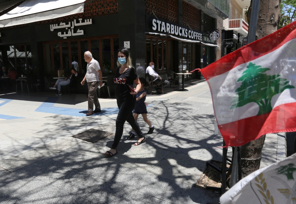 A woman wearing a protective face mask walks past a Starbucks coffee shop in Hamra street, as face masks become compulsory in public as part of the latest measures by authorities to curb the spread of the coronavirus disease (COVID-19), in Beirut, Lebanon