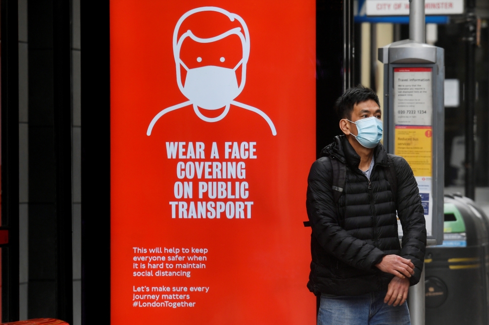 A man wearing a mask waits at a bus stop in London, following the outbreak of the coronavirus disease (COVID-19), London, Britain, June 5, 2020. REUTERS/Toby Melville