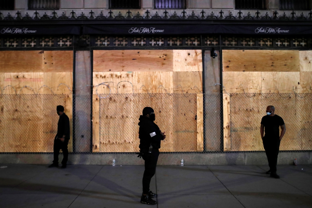 Security guards stand outside Saks Fifth Avenue after the 8 p.m. curfew continued Saturday night in response to looting during the Black Lives Matter's protests in the Manhattan borough of New York City, U.S., June 6, 2020. REUTERS/Andrew Kelly