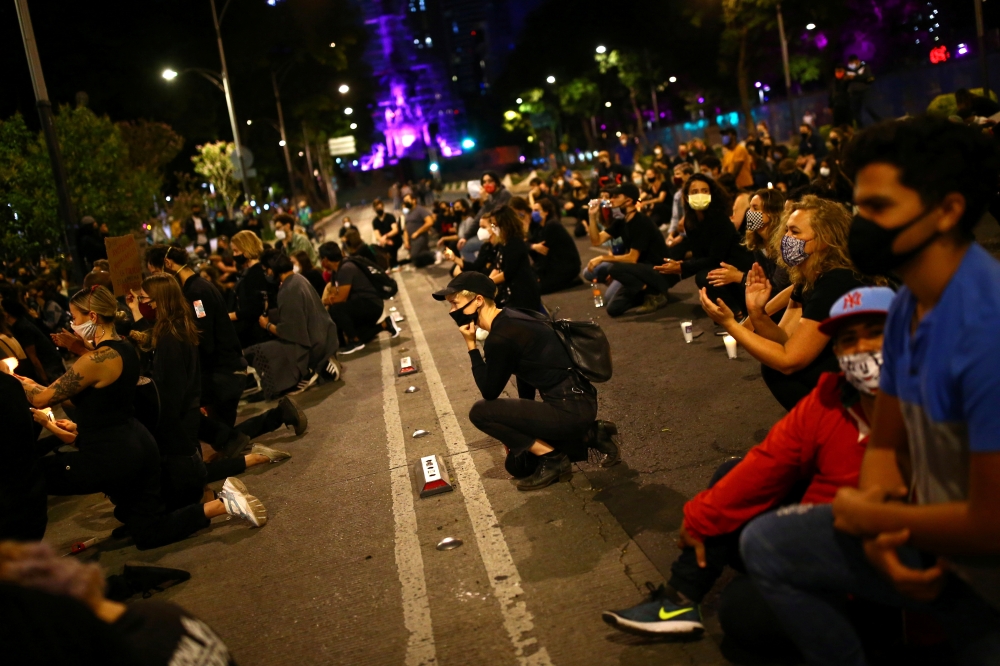 A woman kneels as she participates in a demonstration against the death in Minneapolis police custody of George Floyd, in front of the U.S embassy in Mexico City, Mexico June 4, 2020. REUTERS/Edgard Garrido

