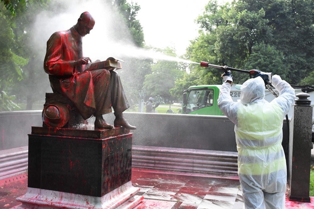 A municipal employee cleans a statue of a famous Italian journalist Indro Montanelli on June 14, 2020 in a Milan public square, a day after it was defaced and stained with red paint. AFP / MIGUEL MEDINA