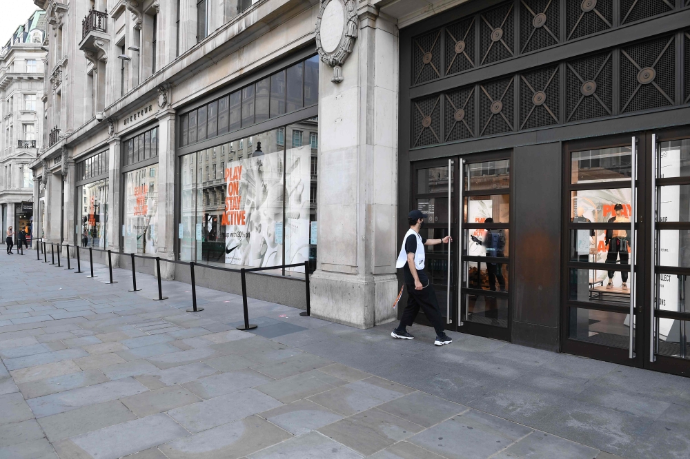 An employee finishes setting out the barriers to aid queuing at Nike Town sports retail store an hour before opening time on Oxford Street in London on June 16, 2020. AFP / JUSTIN TALLIS