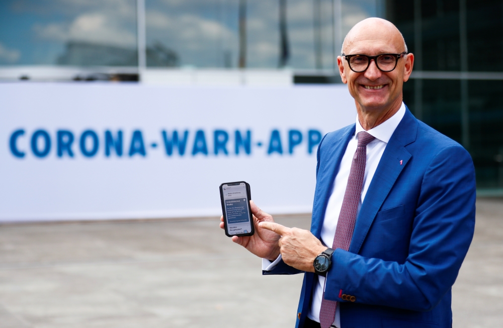 Timotheus Hoettges, CEO of Germany's telecommunications giant Deutsche Telekom AG, holds a mobile phone as he attends the presentation of the new contact-tracing smartphone app in Berlin, Germany, June 16, 2020. REUTERS/Hannibal Hanschke/Pool