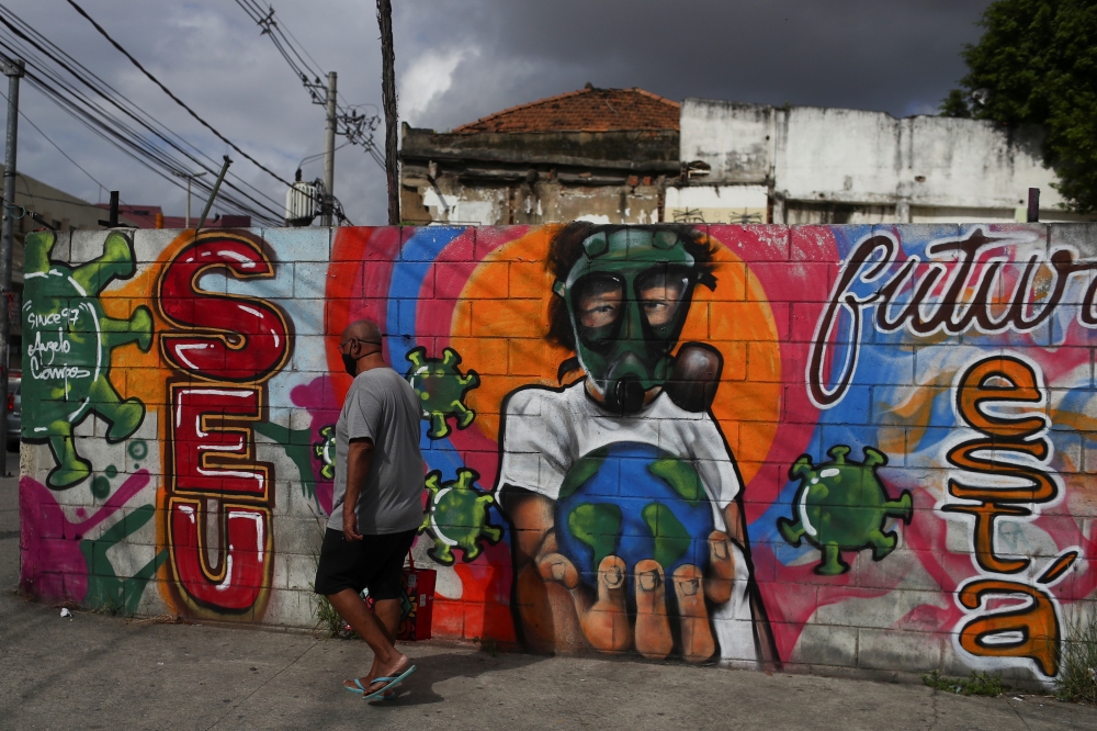A man walks in front of a graffiti of a boy wearing a face mask, amid the coronavirus disease (COVID-19) outbreak in Rio de Janeiro, June 16, 2020. REUTERS/Pilar Olivares