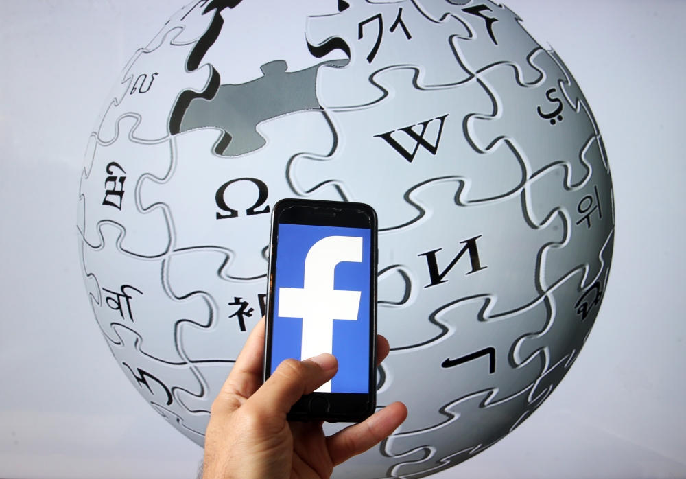  In this illustration photo, the logo of Facebook is displayed on a smartphone as Wikipedia logo at the background in Ankara, Turkey on June 16, 2020. ( Evrim Ayd?n - Anadolu Agency )