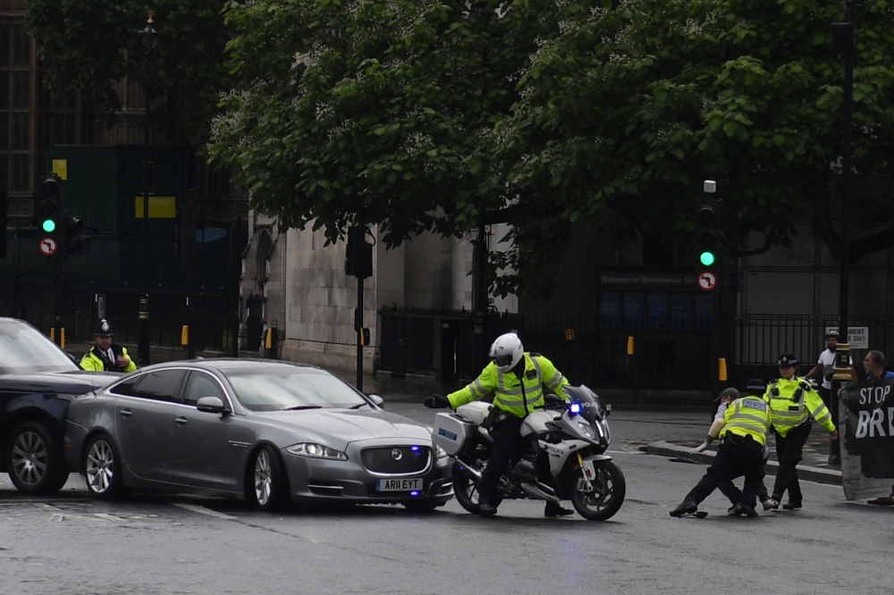A protester from a pro-Kurdish demonstration is stopped and detained by police officers as he ran towards the car of Britain's Prime Minister Boris Johnson (C) as it was leaving with a police escort from the Houses of Parliament in London on June 17, 2020