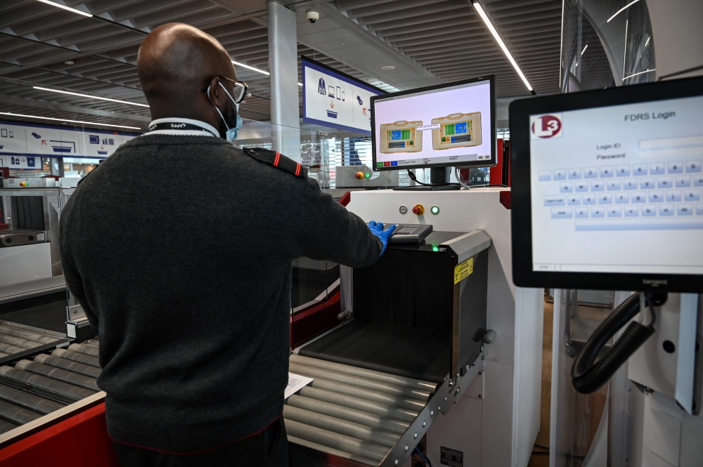 An airport staff member check passengers' luggage passing through X-ray machine at the Terminal 3 of the Orly airport, in Orly on the outskirts of Paris, on June 22, 2020 a few days before its reopening. AFP / BERTRAND GUAY
