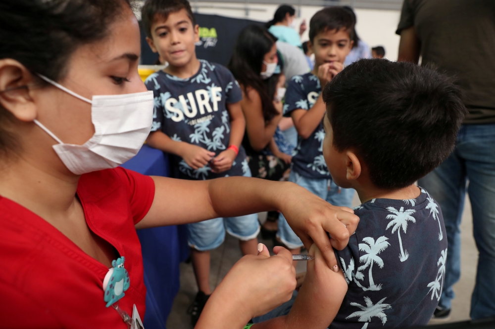 FILE PHOTO: A child receives a vaccination as part of the start of the seasonal flu vaccination campaign as a preventive measure due to the outbreak of coronavirus disease (COVID-19), in Santiago, Chile March 16, 2020. REUTERS/Ivan Alvarado/File Photo