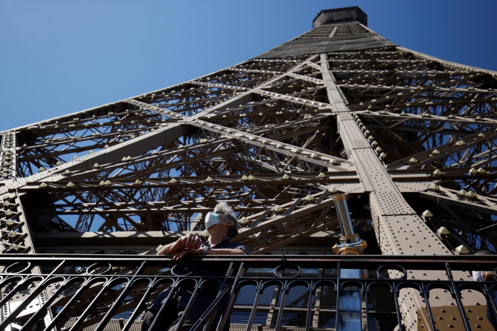 A visitor wearing a protective face mask admires the view from the Eiffel Tower during its partial reopening on June 25, 2020, in Paris. AFP / Thomas SAMSON