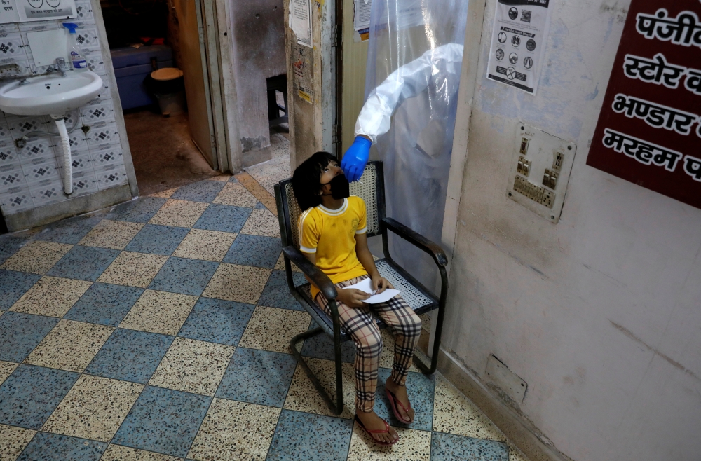 A health worker in personal protective equipment (PPE) collects a sample using a swab from a girl at a local health centre to conduct tests for the coronavirus disease (COVID-19), amid the spread of the disease, in New Delhi, India June 27, 2020. REUTERS/