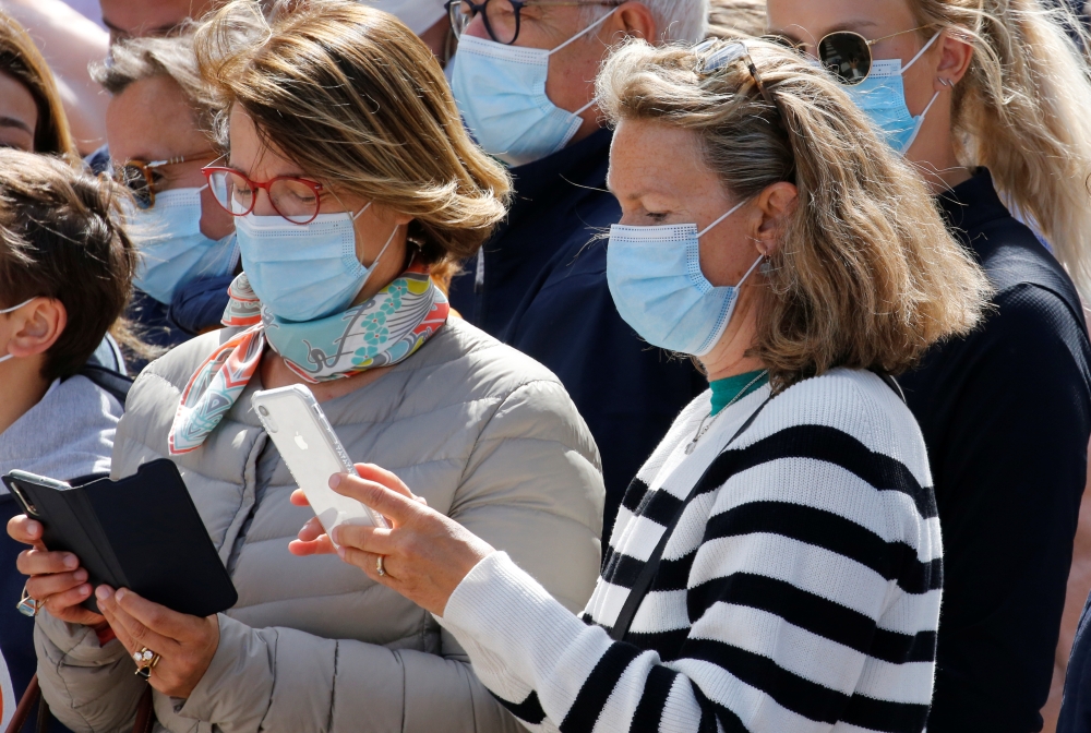 People look at their phones as they wait for French President Emmanuel Macron in his home town of Le Touquet-Paris-Plage during the second round of French municipal elections, in France June 28, 2020. REUTERS/Pascal Rossignol