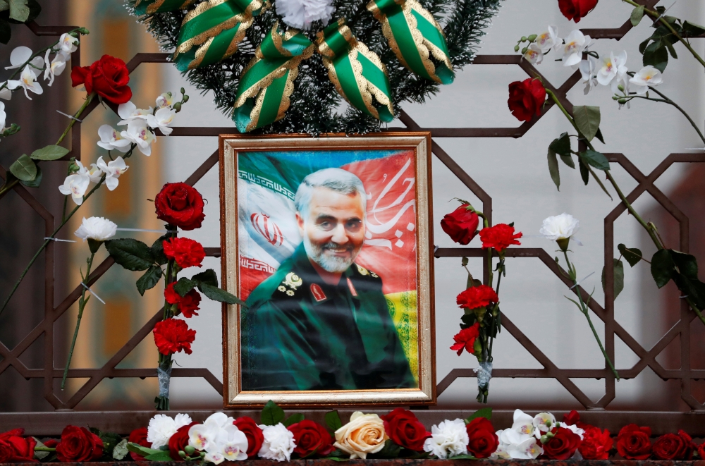 FILE PHOTO: Flowers lie around a portrait of Iranian Major-General Qassem Soleimani, who was killed in an airstrike near Baghdad, at the Iranian embassy's fence in Minsk, Belarus January 10, 2020. REUTERS/Vasily Fedosenko/File Photo