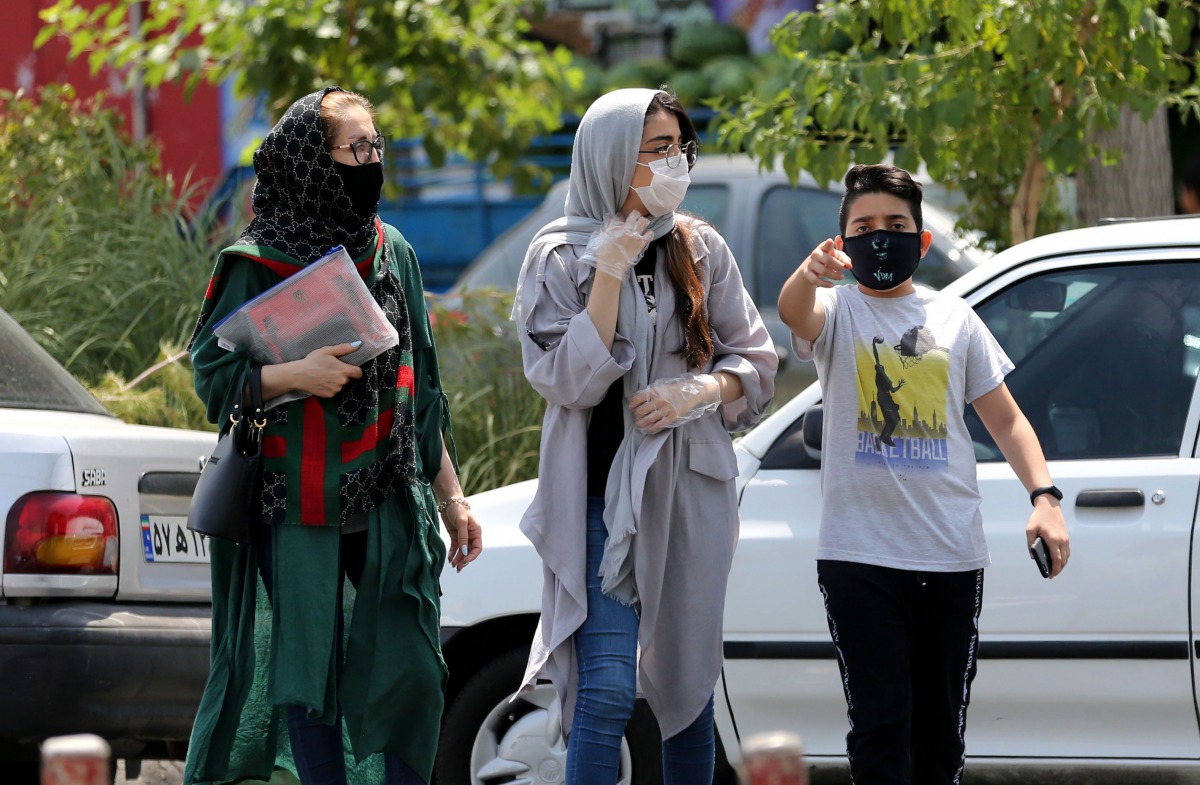 Pedestrians, wearing protective masks due to the COVID-19 coronavirus, walk past shops in the Iranian capital Tehran on June 28, 2020.  / AFP / ATTA KENARE