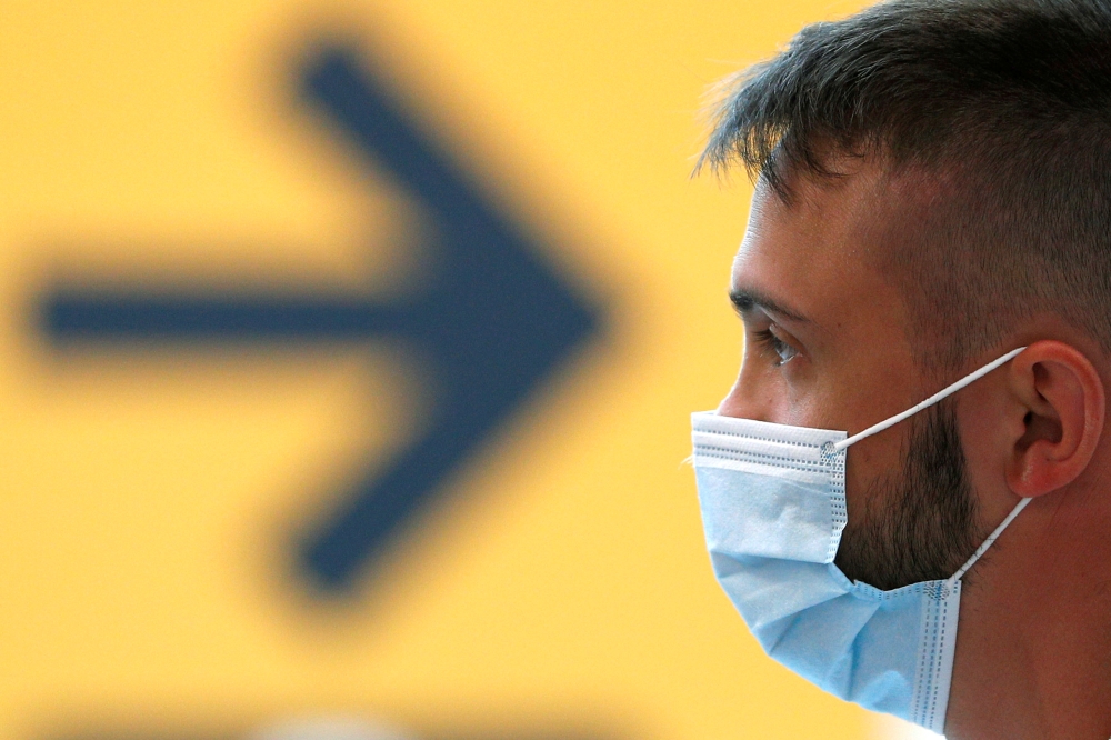 A passenger wearing a protective face mask waits for his flight at Fiumicino Airport, one of the two airports in the world to obtain the 'Biosafety Trust certification' for the correct application of security measures to prevent infections, following the 