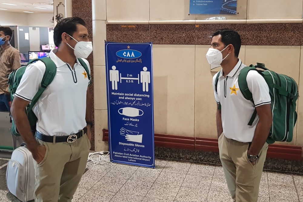 In this handout picture released and taken by Pakistan Cricket Board (PCB) on June 28, 2020, Pakistani cricketers Sarfaraz Ahmed (L), and Asad Shafiq wearing facemasks arrive at the Allama Iqbal International airport before their departure to England, in 
