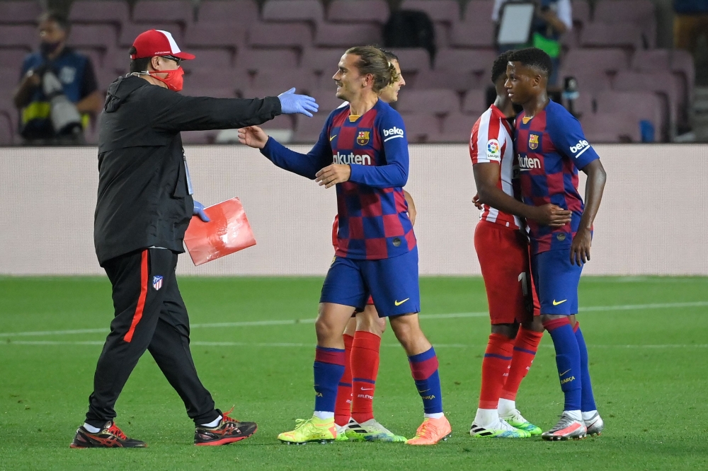An Atletico Madrid staff member greets Barcelona's French forward Antoine Griezmann (C) at the end of the Spanish League football match between FC Barcelona and Club Atletico de Madrid at the Camp Nou stadium in Barcelona on June 30, 2020. / AFP / LLUIS G