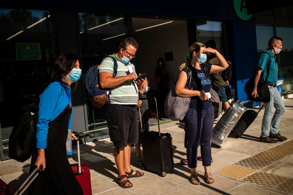 Passengers of a flight from Budapest wearing protective face masks arrive at the Corfu Airport Ioannis Kapodistrias on Corfu Island on July 1, 2020, on its reopening day following months of closure due to the sanitary measures taken to curb the spread of 