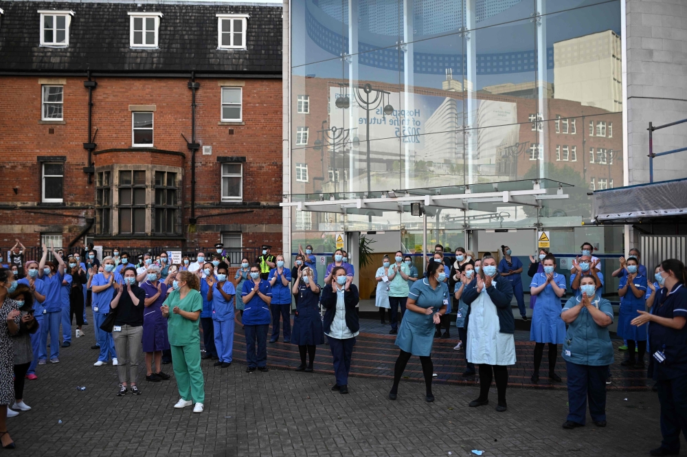 Members of the emergency services and staff of the Leeds General Infirmary participate in a national NHS (National Health Service) celebration clap outside the hospital in Leeds on July 5, 2020, to mark its 72nd anniversary. / AFP / Oli SCARFF
