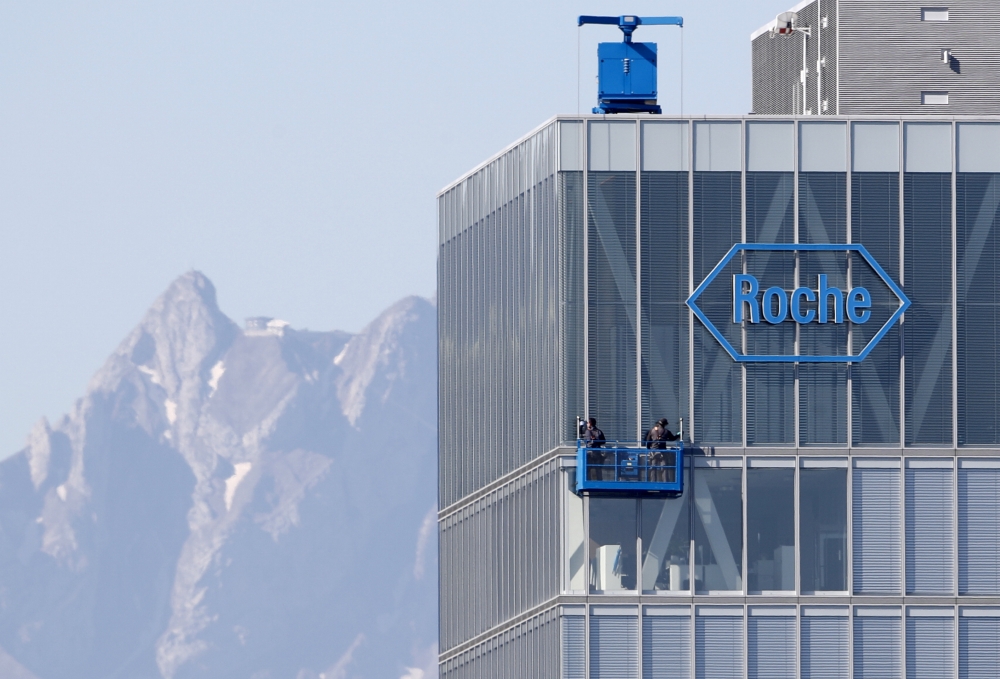 FILE PHOTO: The peak of Mount Pilatus is seen in the background as workers clean the windows of a building of Roche in Rotkreuz May 27, 2020. REUTERS/Arnd Wiegmann 