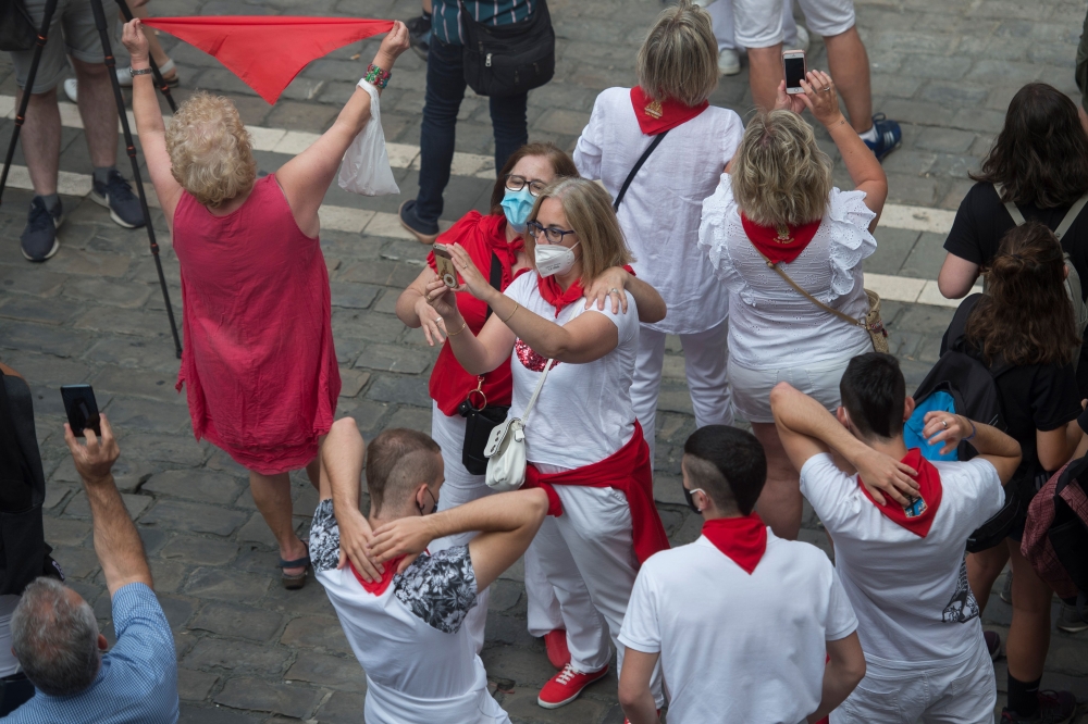 Revellers wearing face masks attend symbolic celebrations for the suspended 'Chupinazo' opening ceremony to mark what was supposed to be the kick-off of the San Fermin Festival outside the Town Hall of Pamplona in northern Spain on July 6, 2020. / AFP / A