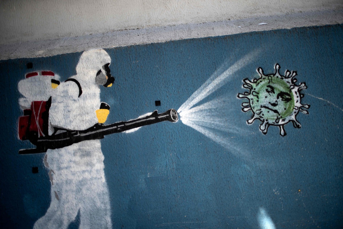 TOPSHOT - View of a mural depicting a man in protective suit spraying disinfectant on a coronavirus with Brazilian President Jair Bolsonaro's face, at the Tijuca neighborhood in RIO DE JANEIRO, Brazil on July 8, 2020, amid the new coronavirus pandemic. Br