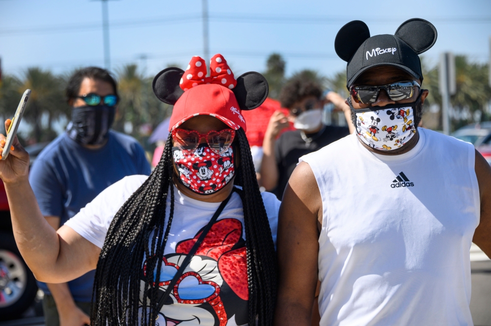 A couple waits in line to enter Downtown Disney in Anaheim, California on July 9, 2020, the first day the outdoor shopping and dining complex has been open to the public since it closed in mid-March amid the COVID-19 pandemic. (AFP / Robyn Beck)