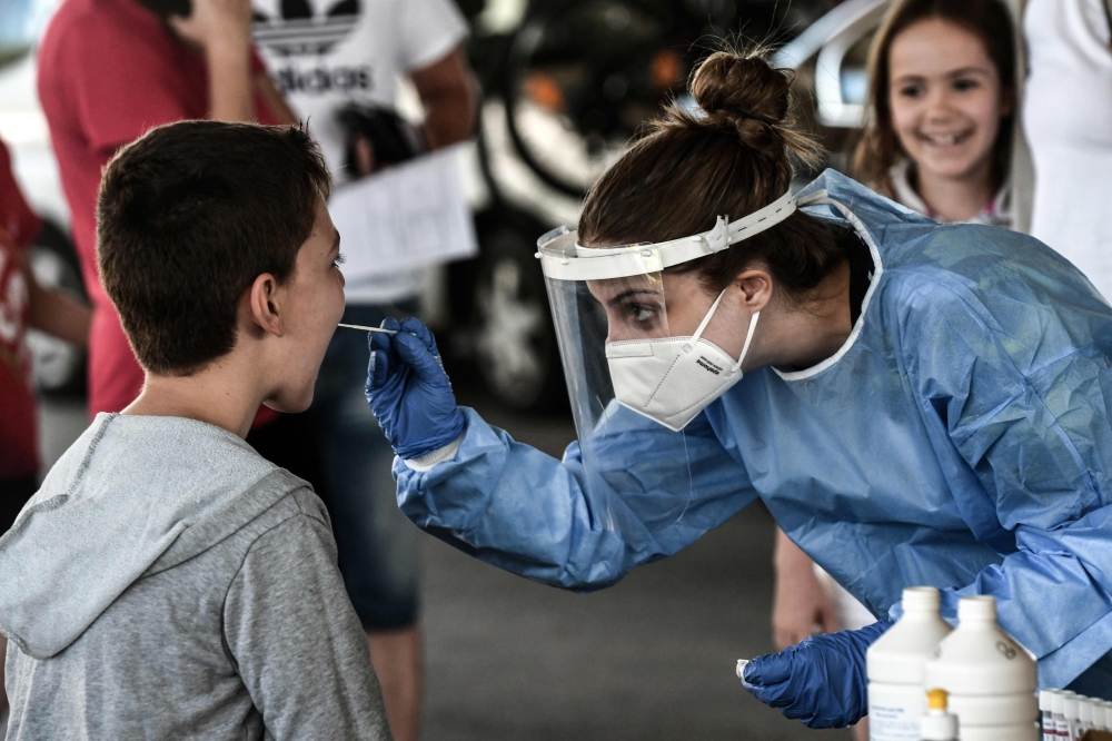 A public health worker collects a swab sample from a boy to test for the COVID-19, the novel coronavirus, at the Greek-Bulgarian border crossing in Promachonas on July 10, 2020. / AFP / Sakis MITROLIDIS
