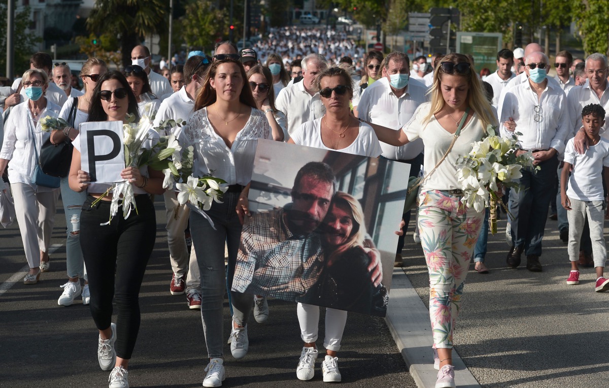 Veronique Monguillot (C), wife of bus driver Philippe Monguillot, declared brain dead after being attacked for refusing to let aboard a group of people who were not wearing face masks, holds a picture of her husband during a white march in Bayonne, southw