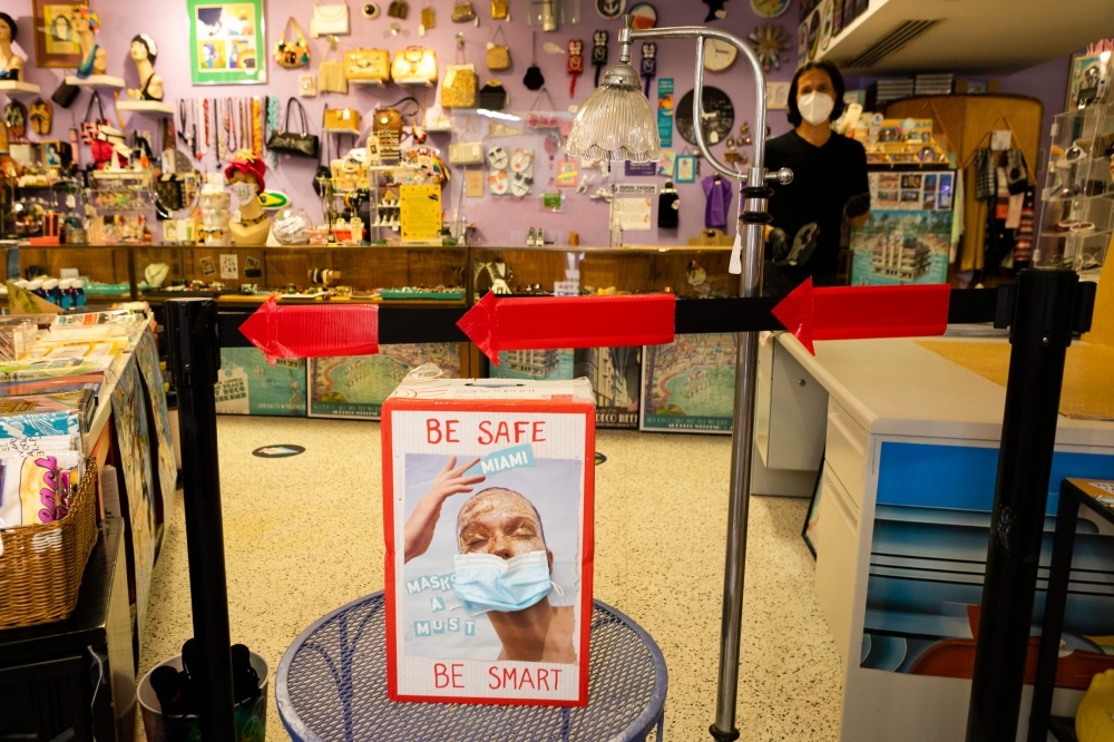 (FILES) In this file photo a sign with a facemask promoting COVID-19 safety measures is seen in a store in Miami Beach, Florida on June 16, 2020./ AFP / Eva Marie UZCATEGUI
