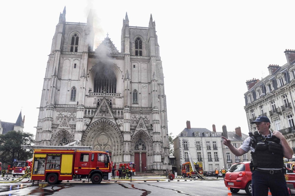 A French Police officer gestures as firefighters are at work to put out a fire at the Saint-Pierre-et-Saint-Paul cathedral in Nantes, western France, on July 18, 2020. AFP / Sebastien Salom-Gomis 