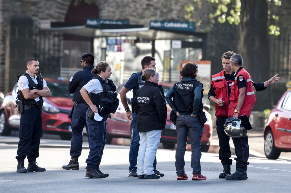 Firefighters and scientific police officers speak in front of the Saint-Pierre-et-Saint-Paul cathedral in Nantes, western France, on July 19, 2020. French investigators were on SJuly 19 questioning a man who worked at the cathedral in the city of Nantes w