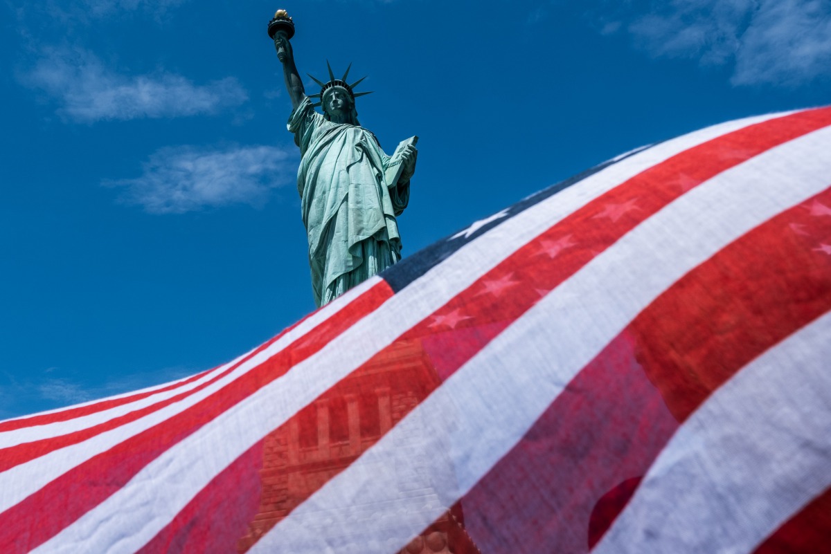 NEW YORK, NY - JULY 20: The Statue of Liberty is seen over a wind blown American flag scarf on Liberty Island on July 20, 2020 in New York City. Liberty Island partially reopens months after the attraction was shut down due to the coronavirus pandemic. Je
