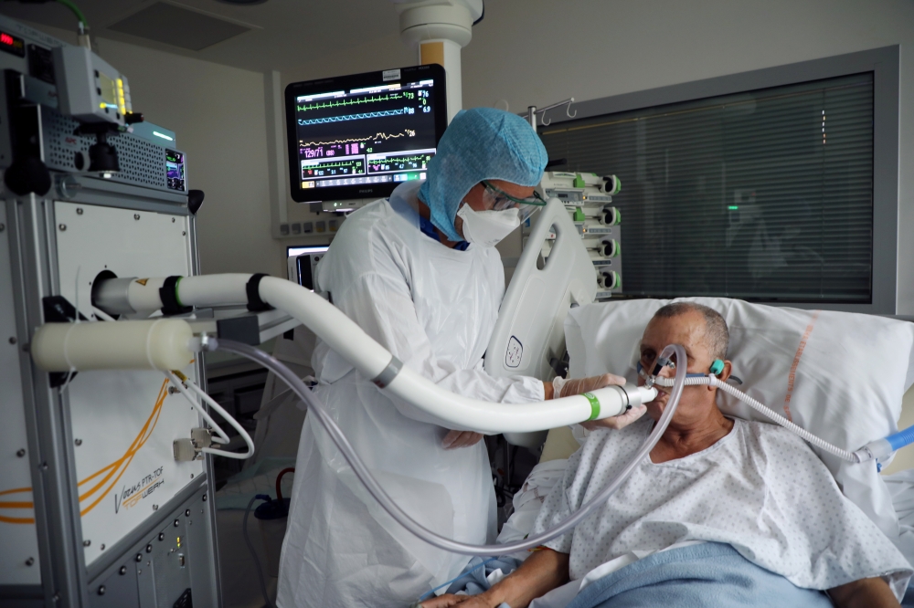 Christian George, Director of Research at the National Centre of Scientific Research, helps a patient suffering from coronavirus disease (COVID-19) to use the COVID-19 'Breathalyzer' test machine at the La Croix-Rousse Hospital in Lyon, France, July 22, 2