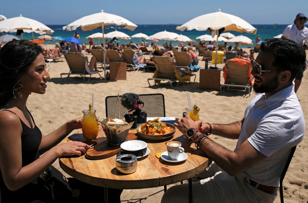 FILE PHOTO: A woman and a man sit in a bar as they enjoy the sunny weather at Barceloneta beach, after Catalonia's regional authorities and the city council announced restrictions to contain the spread of the coronavirus disease (COVID-19) in Barcelona, S