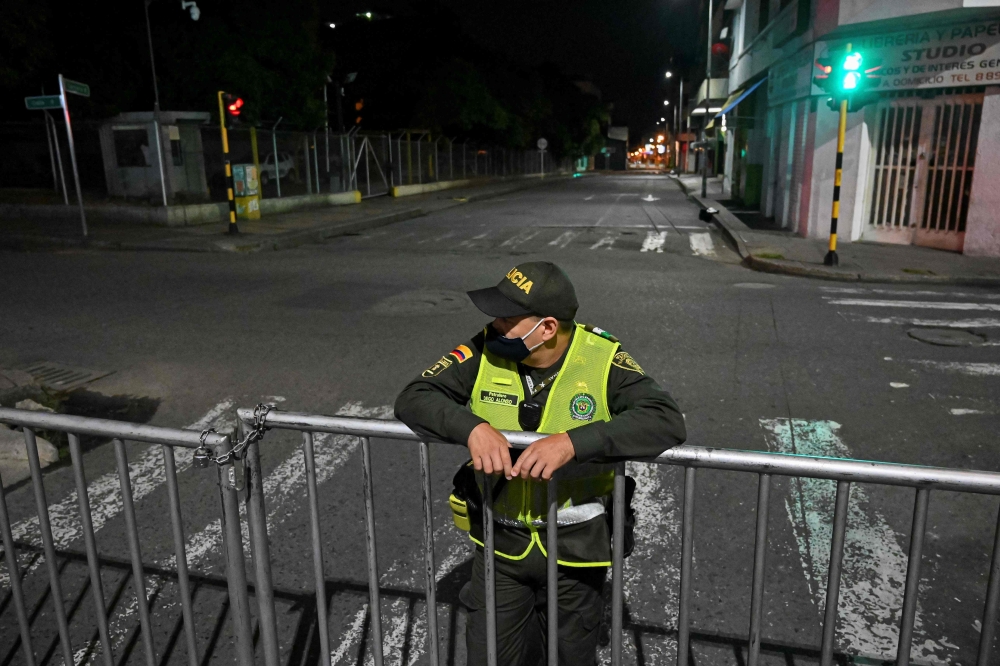 A colombian police officer guards an empty street during a curfew imposed in neighbourhoods due to high numbers of COVID-19 cases in Cali, Colombia on July 24, 2020. AFP / Luis ROBAYO