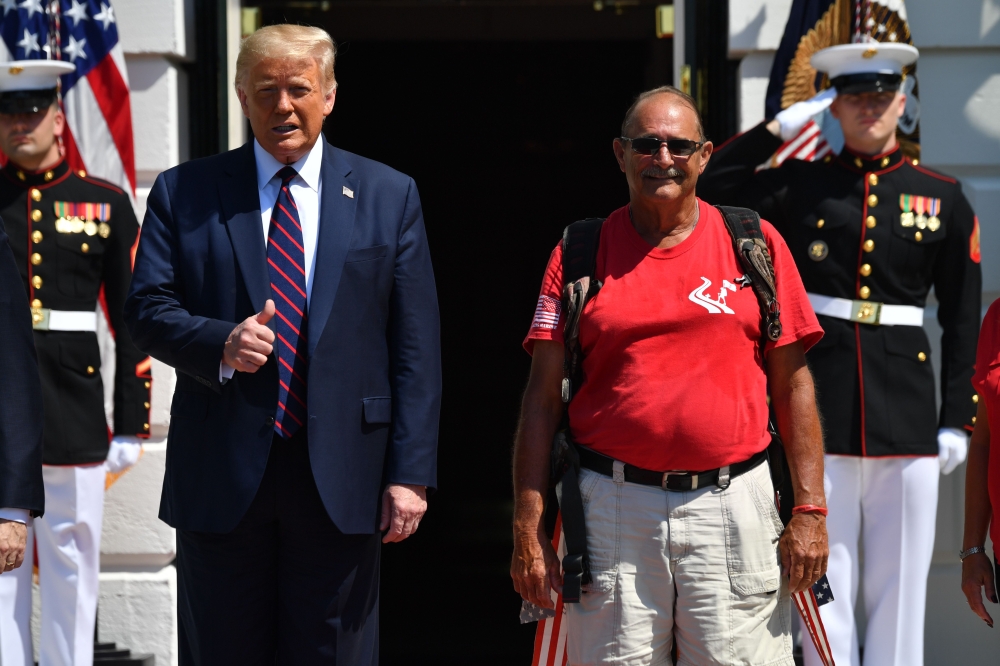US President Donald Trump greets Marine veteran Terry Sharpe(C), who walked from North Carolina to Washington to raise awareness about veterans' suicides, at the White House in Washington, DC, on July 27, 2020. Terry often refers to his walk as “300 Miles