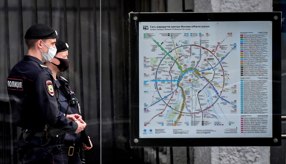 Two police officers wearing a protective face mask patrol in the streets in central Moscow on July 28, 2020, amid the COVID-19 pandemic, caused by the novel coronavirus. / AFP / Yuri KADOBNOV