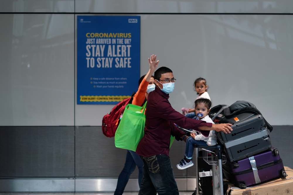 Travellers wearing face masks walk at the Terminal 5 at Heathrow Airport, as the spread of the coronavirus disease (COVID-19) continues, in London, Britain, July 26, 2020. REUTERS/Henry Nicholls