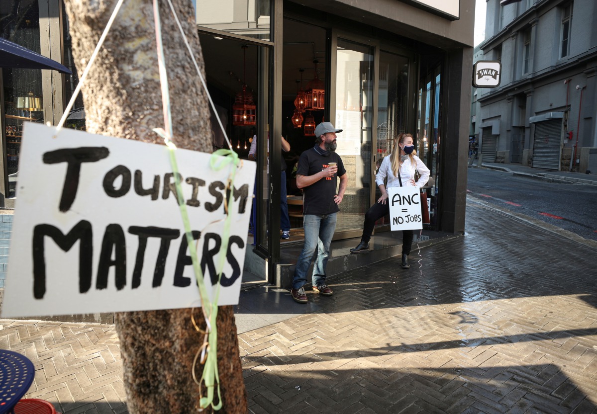 Restaurant workers look on after police used a water canon to disperse demonstrators protesting against coronavirus disease (COVID-19) lockdown regulations in Cape Town, South Africa, July 24, 2020. REUTERS/Mike Hutchings