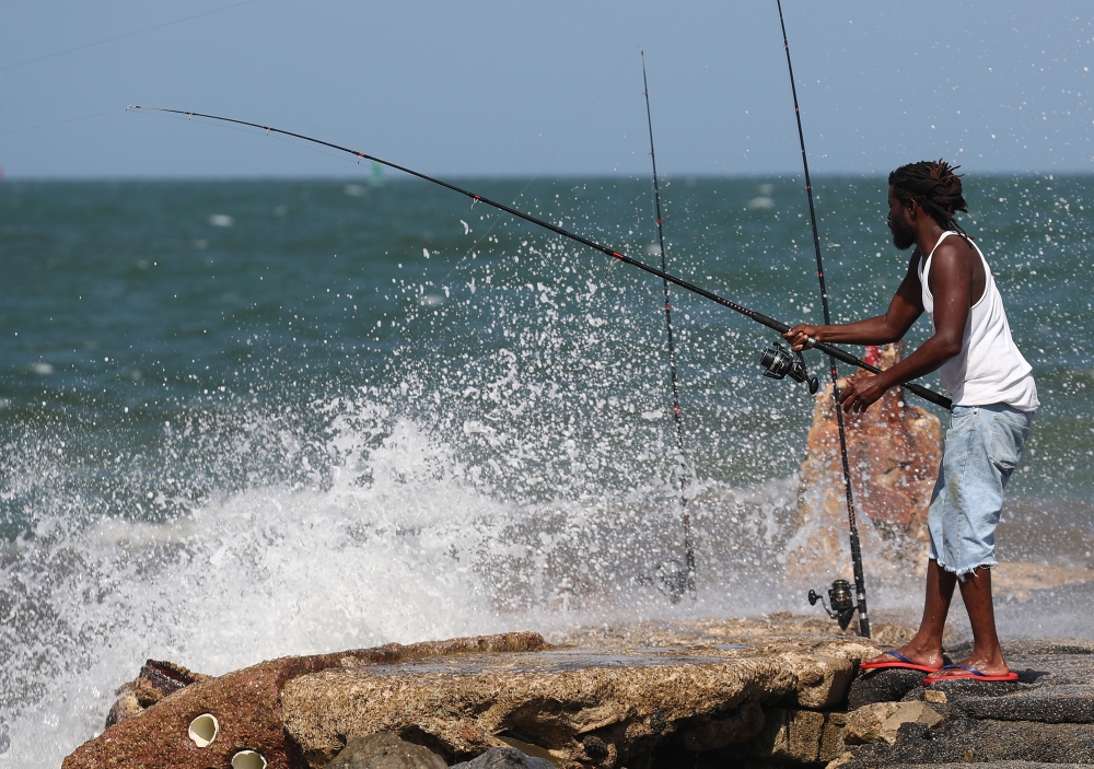 Harold Dixon fishes near crashing waves along the jetty as Tropical Storm Isaias approaches on August 01, 2020 in Fort Pierce, Florida.  . Joe Raedle/AFP