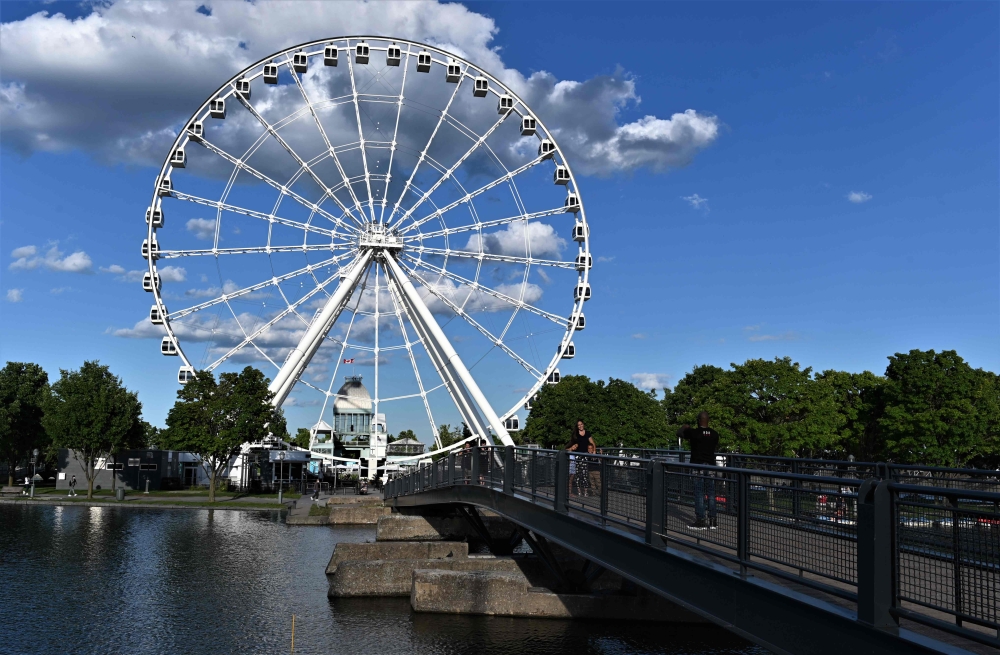 People take pictures in front of Ferris Wheel in the Old-Port, Montreal, Canada, on July 28, 2020. AFP / Eric Thomas 
 