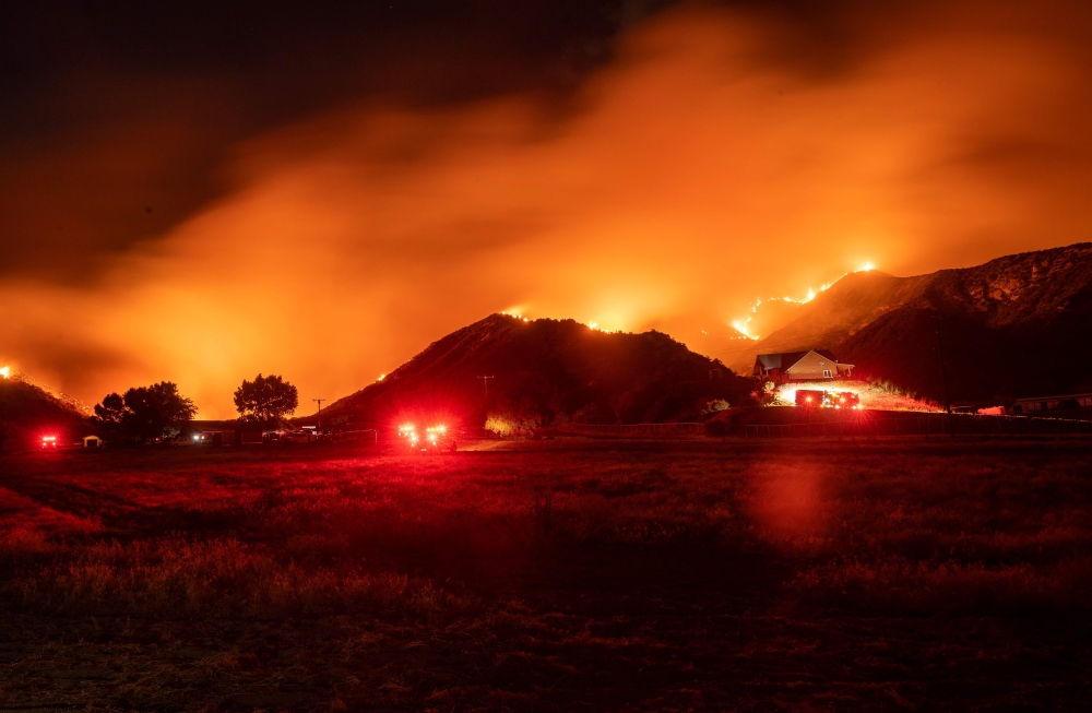 In this long exposure photograph, firefighters monitor flames as they skirt a hillside near a residential area during the Apple fire in Banning, California on August 1, 2020. 4,125 acres have burn in Cherry Valley, about 2,000 people have received evacuat