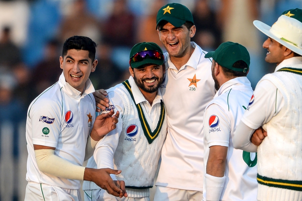 This file photo taken on February 7, 2020 shows Pakistan's Azhar Ali (2nd L) celebrating with teammates Naseem Shah (L) and Shaheen Shah Afridi (3rd L) after the dismissal of Bangladesh's Mohammad Mithun (unseen) during the first day of the first cricket 