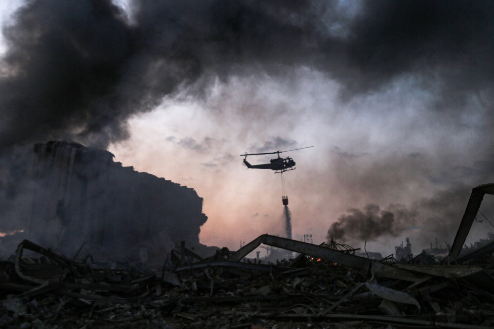  A helicopter puts out a fire at the scene of an explosion at the port of Lebanon's capital Beirut on August 4, 2020. / AFP / STR