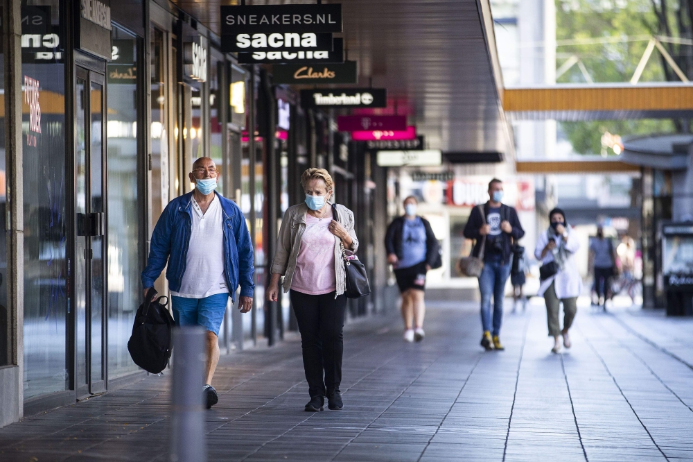 People wearing a face mask walks on the Lijnbaan, in Rotterdam on August 5, 2020, as from today, wearing a face mask is mandatory in five usually crowded places in the city.  AFP / Pieter STAM DE JONGE
